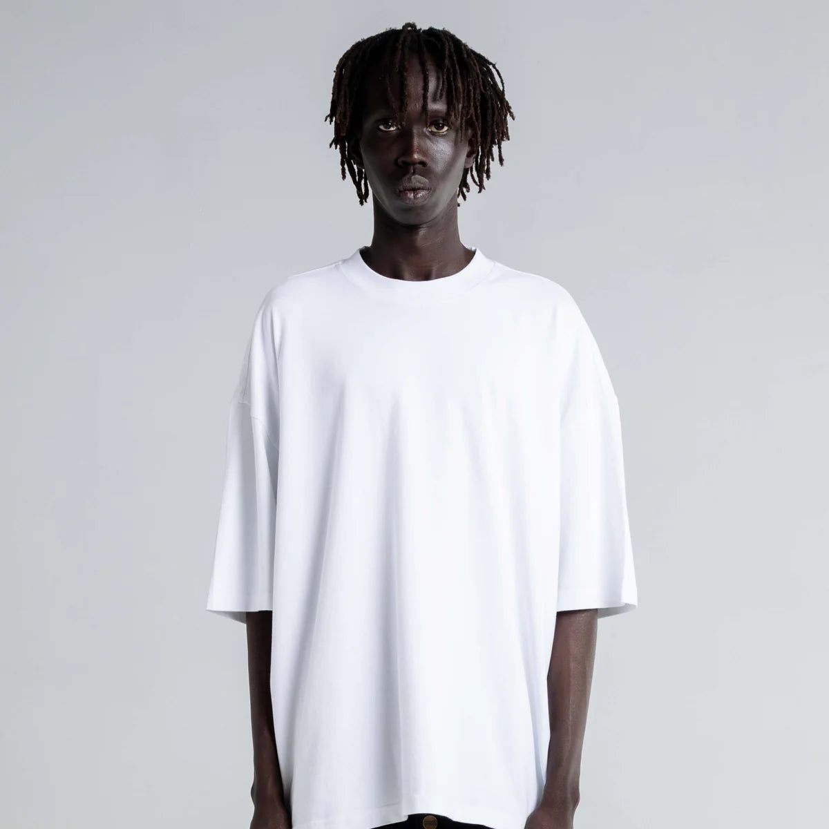 Person wearing a white t-shirt and black pants on a plain background