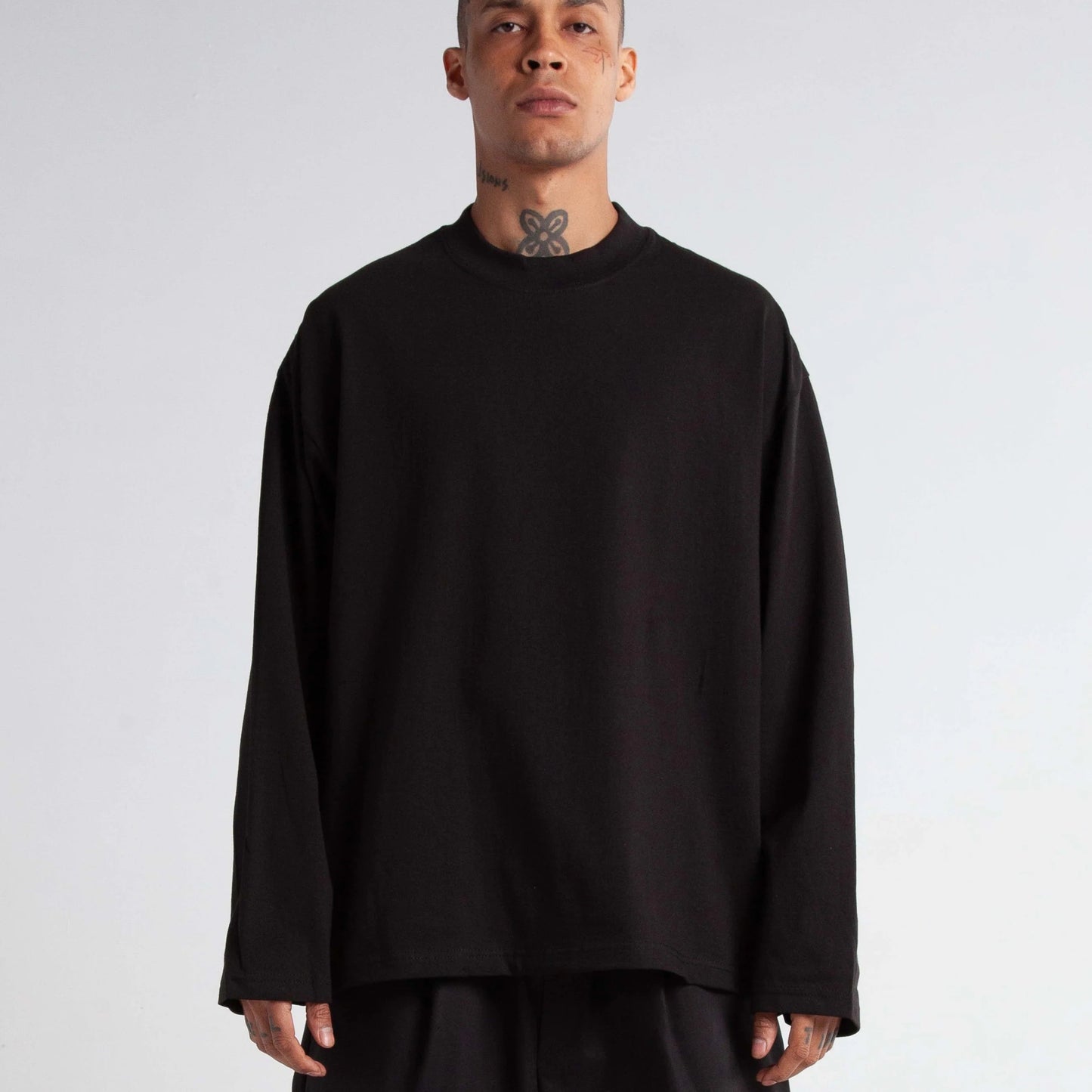 Man wearing a black oversized sweater and pants on a plain background