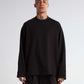 Man wearing a black oversized sweater and pants on a plain background
