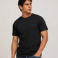 A man wearing a plain black short-sleeve crewneck t-shirt and blue jeans, standing against a light gray studio background.