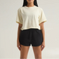 Person wearing a beige t-shirt and black shorts on a plain background