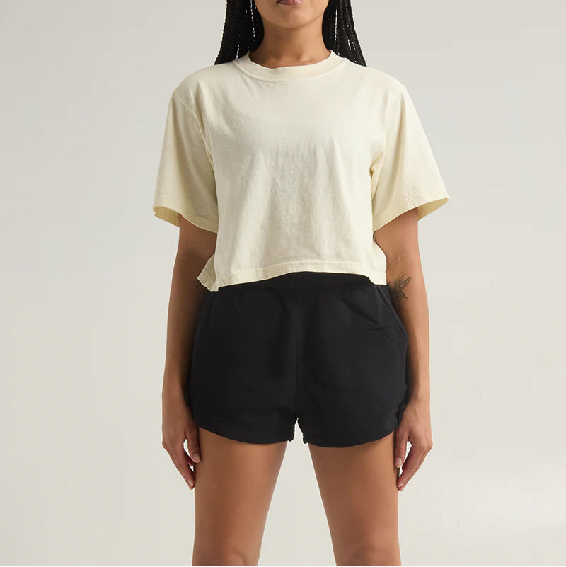 Person wearing a beige t-shirt and black shorts on a plain background