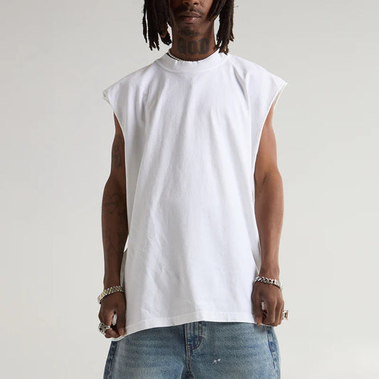 Man wearing a white sleeveless shirt and blue jeans against a plain background